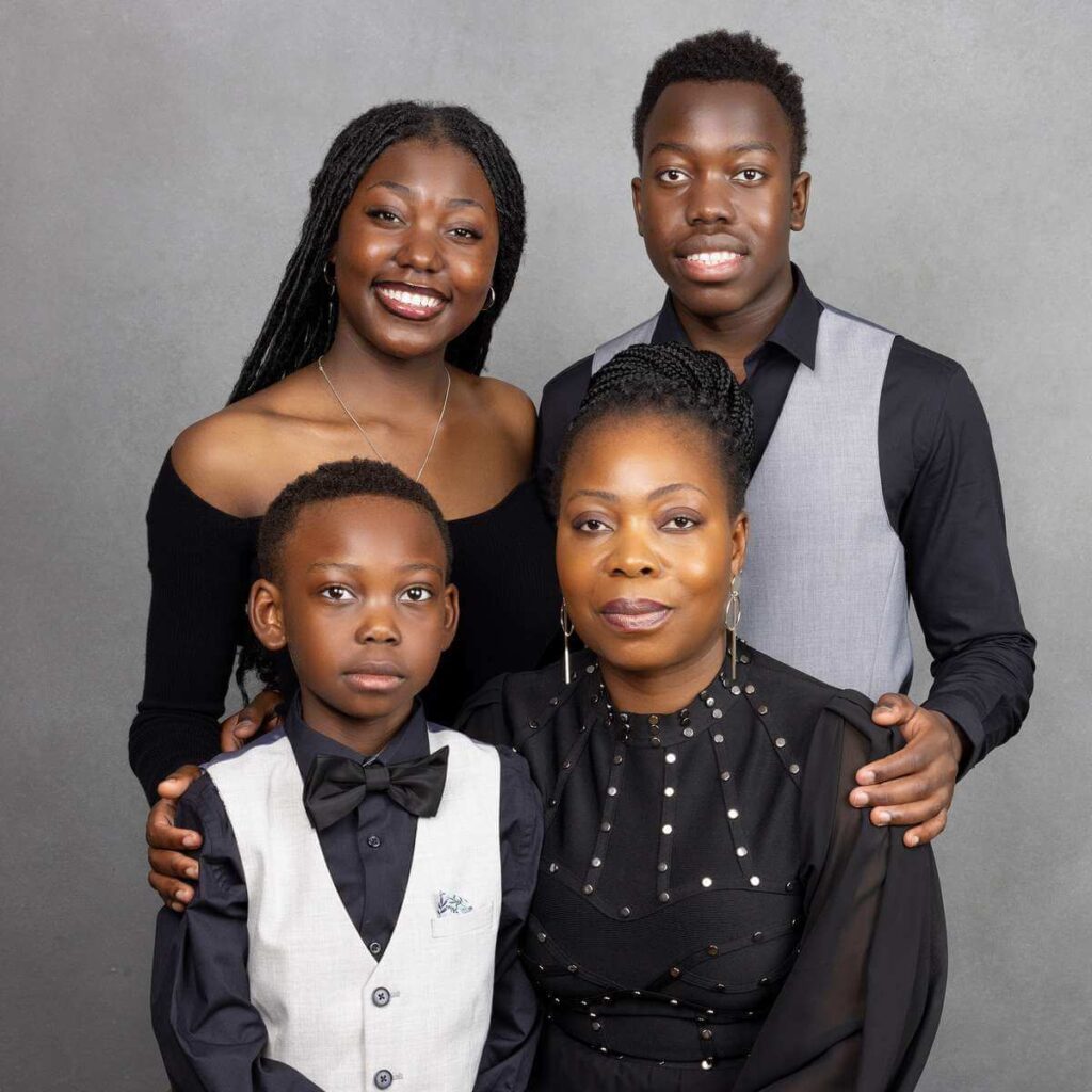 A group of people smiling and posing for a photo indoors against a wall, showcasing their clothing and friendship.
